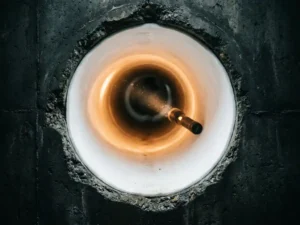 Frisch installierter weißer Rohrliner im Querschnitt eines unterirdischen Betonrohrs, beleuchtet von einer Inspektionsleuchte.